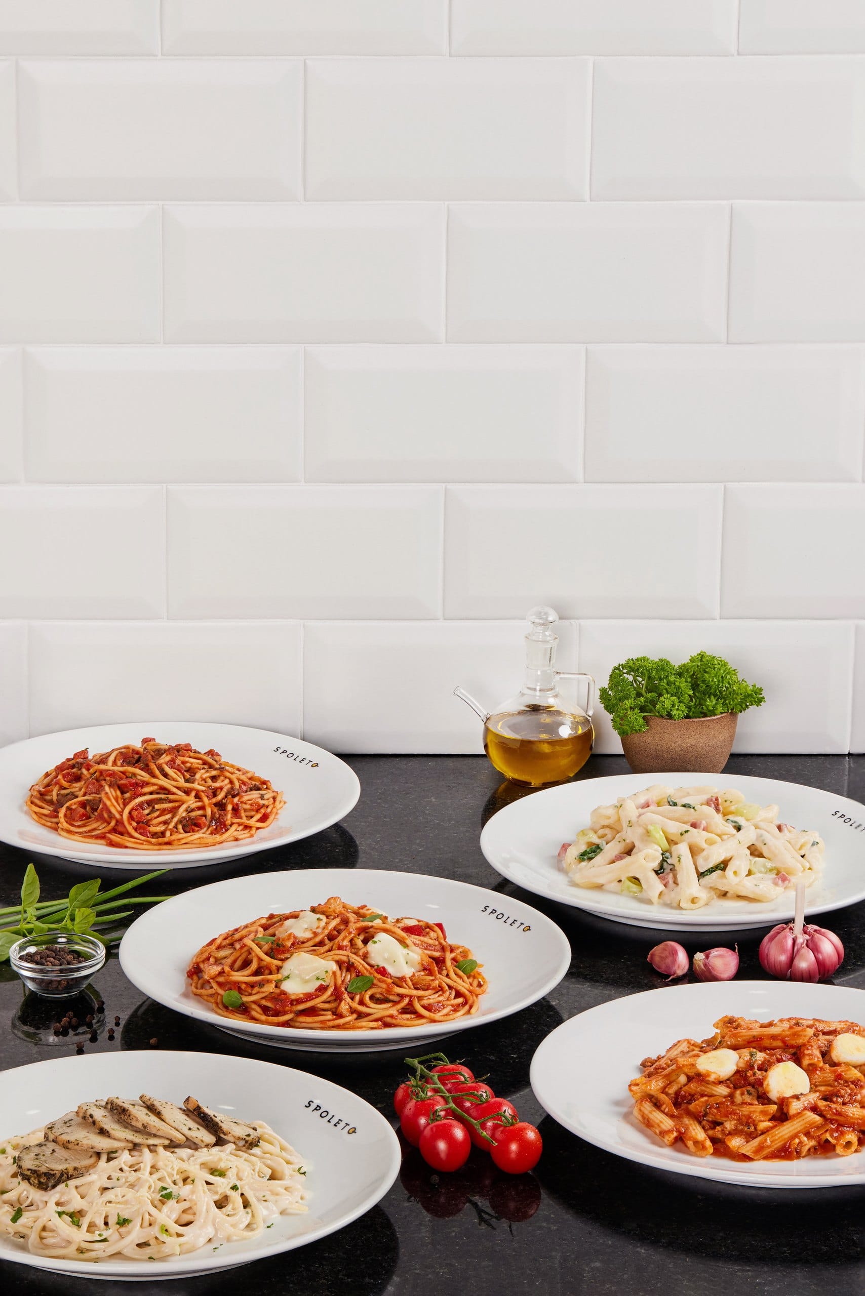 Prato de penne com molho branco, ao lado de azeite e salsa