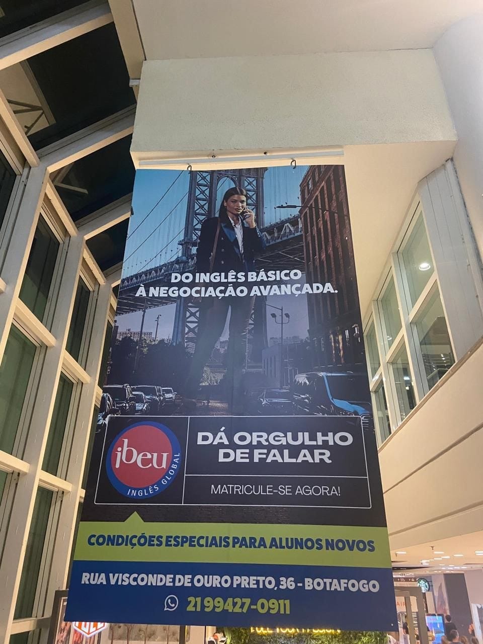 Banner vertical do Ibeu pendurado numa fachada, com a frase Do inglês básico à negociação avançada