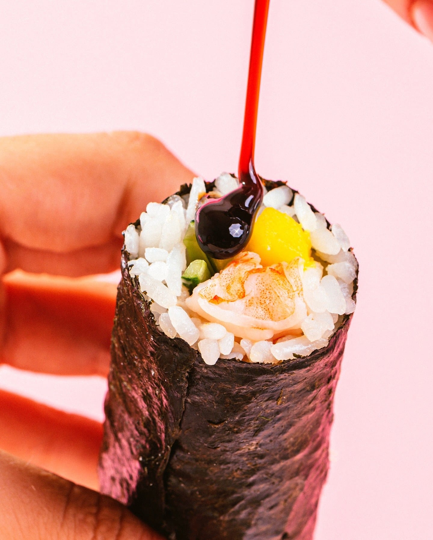 Shoyu pingando sobre um hand roll de salmão e manga