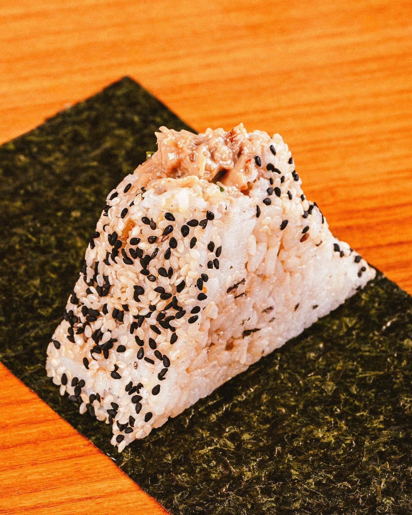 Onigiri de arroz com gergelim preto sobre a folha de alga